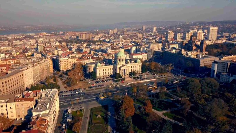 Aerial view of Belgrade with historic buildings, roads, parks, and the city skyline.